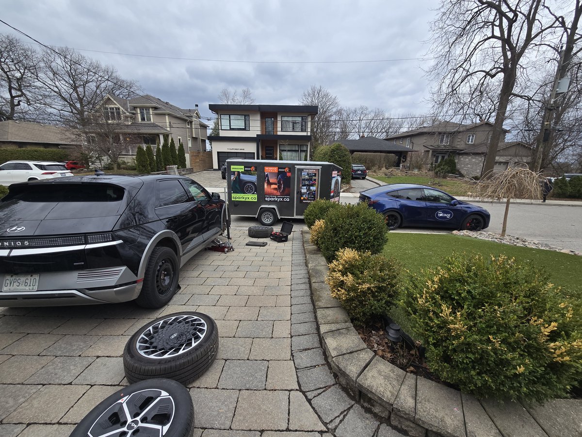 Black Hyundai IONIQ 5 with its wheel removed during a driveway tire service
